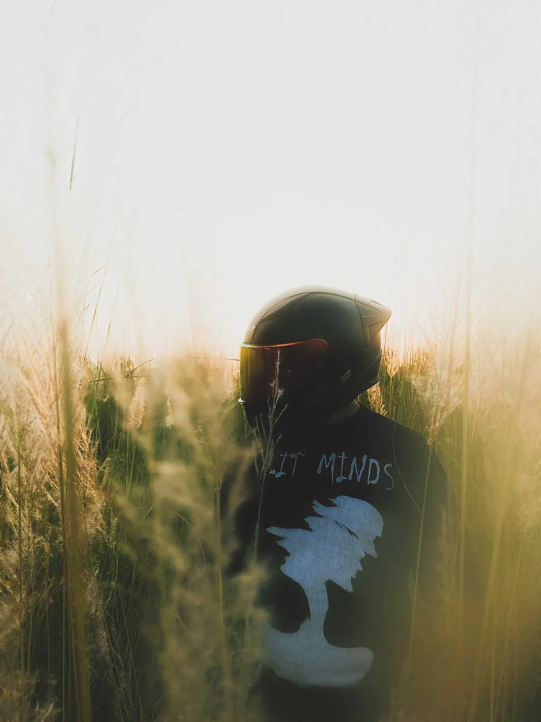 Raheel in his helmet with an orange visor, standing in tall grass